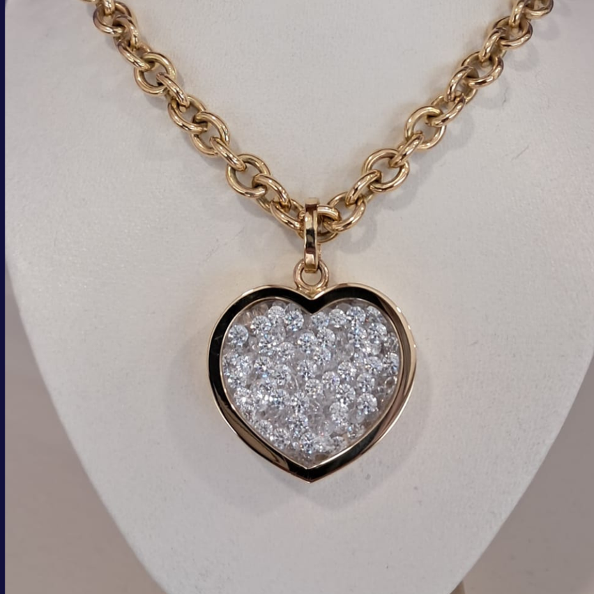 Eine goldene Kettenkette mit einem herzförmigen Anhänger, der mehrere Diamanten auf einem weißen Mannequin zeigt.