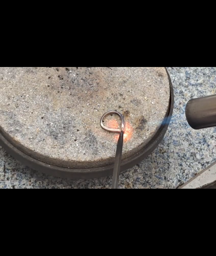 Ein Metallring auf einer Steinoberfläche wird mit einer Fackel erhitzt und gibt eine helle Flamme ab.
