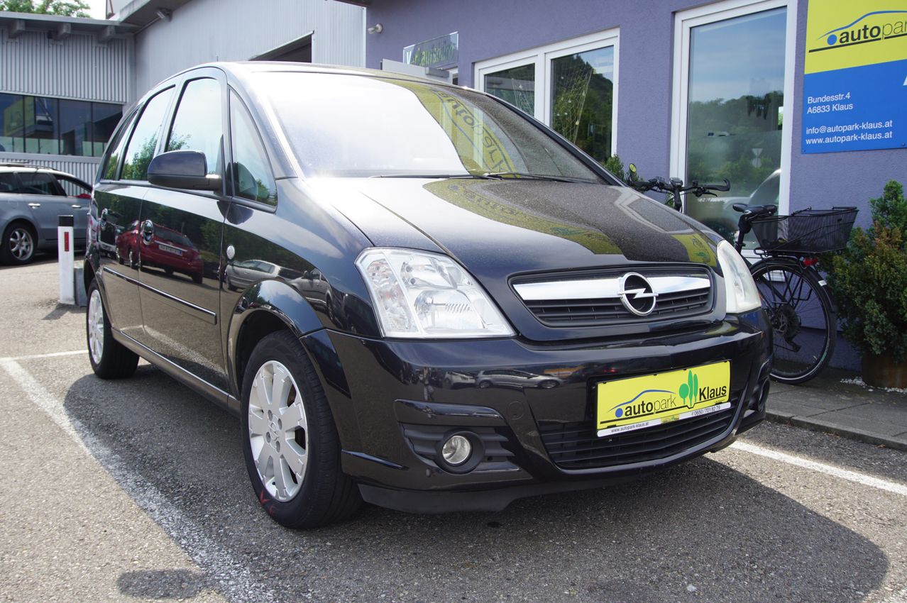 Ein schwarzer Opel Meriva steht vor einem Gebäude mit einem gelben Nummernschild, auf dem 'autopark Klaus' steht.