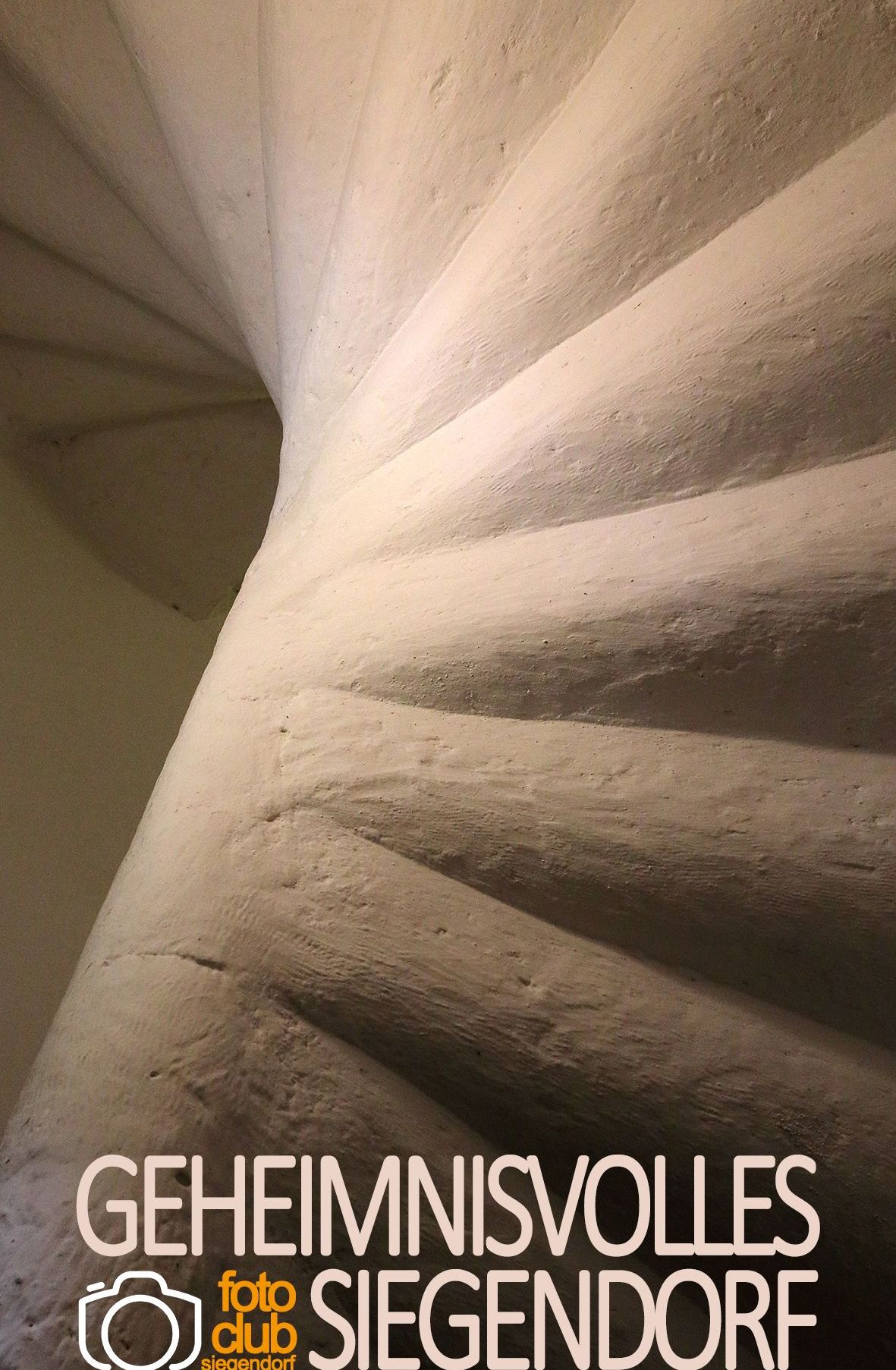 Eine Nahaufnahme einer Wendeltreppe mit weißen Stufen und einer zentralen Stütze. Die Stufen haben eine leichte Textur und Abnutzungsspuren.