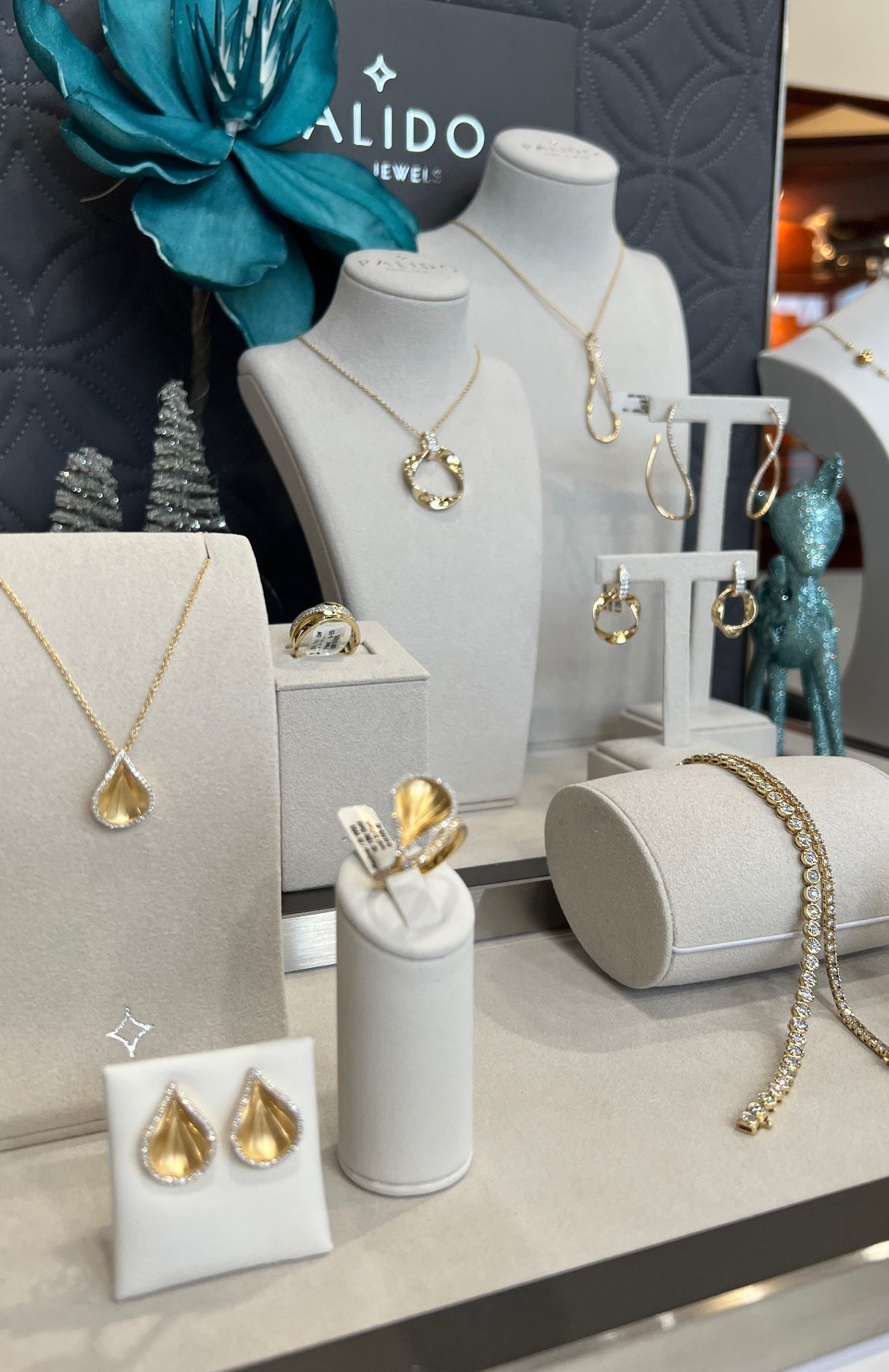 Eine Schmuckausstellung mit verschiedenen Stücken auf Mannequins und Podesten, einschließlich Halsketten, Ringen und Ohrringen, einige mit Kristallen verziert.