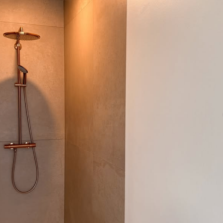 Eine Kupferdusche ist an der Wand befestigt.