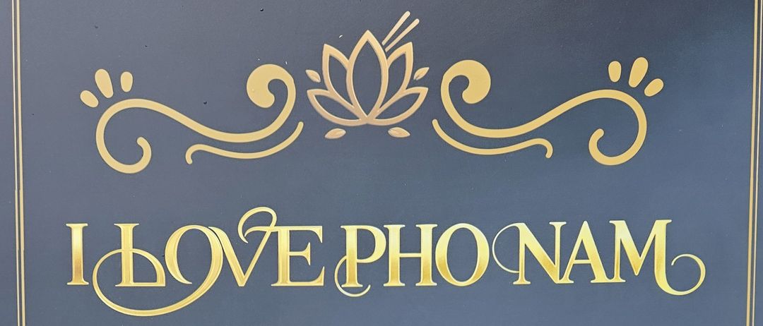 Ein blaues Plakat bewirbt ein vietnamesisches Restaurant, das frische, leichte und gesunde Mahlzeiten anbietet, zubereitet nach dem traditionellen Rezept der Mama. Es zeigt vietnamesische Frühlingsrollen und andere Gerichte.