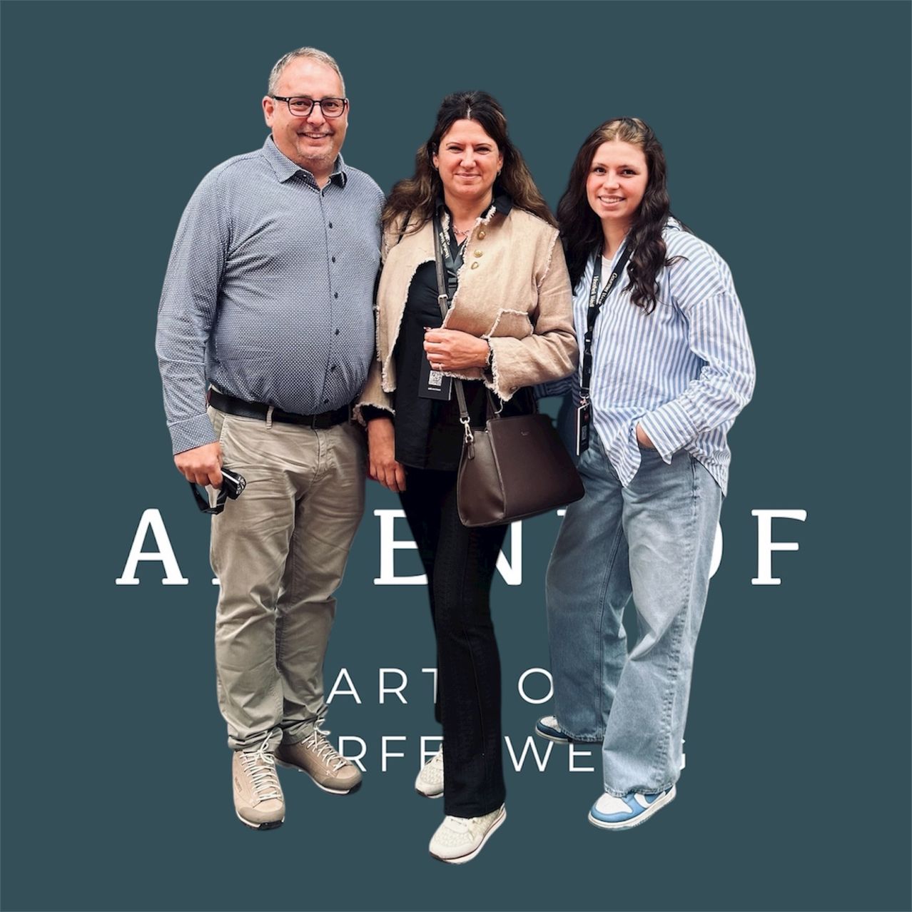 Drei Menschen stehen eng beieinander, lächeln und posieren für ein Foto. Sie tragen alle verschiedene Kleidungsstücke. Der Mann trägt einen Gürtel, und die Frau trägt eine Handtasche. Hinter ihnen ist eine grüne Wand mit weißem Text.