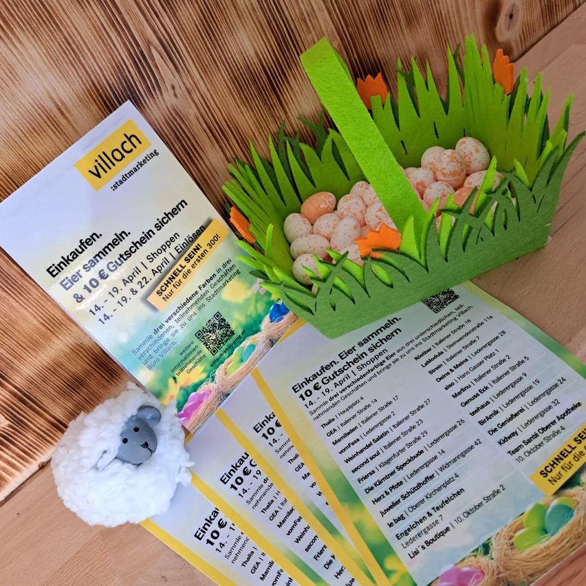 Ein Papierkorb mit Eiern, einem Plüschtier und zwei Broschüren mit Informationen zu Osteraktivitäten und einem Gutschein für einen 10€-Rabatt auf Einkäufe in der Innenstadt.