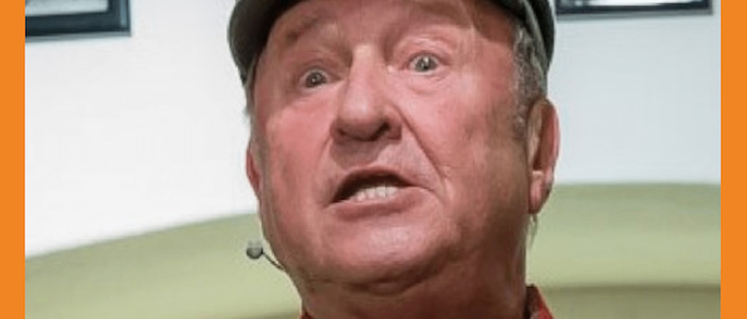 Ein Mann, der als Soldat verkleidet ist und einen Hut trägt, schreit vor einer weißen Wand.