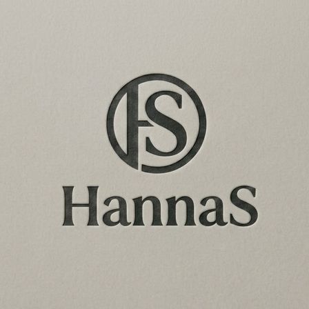 Ein Logo für Hannas, mit einem stilisierten 'S' in einem Kreis, darunter steht 'Hannas' in fetter Schrift.