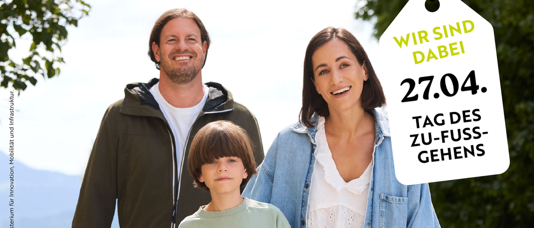 Eine Familie geht lächelnd mit einem Einkaufsbeutel spazieren. Ein Schild sagt 'Willst du mit mir gehen?' und 'Gemeinsam macht am meisten Spaß'. Ein anderes Schild sagt 'Wir sind dabei', 'Tag des Zu-Fuß-Gehens', '27.04'.