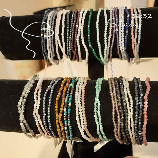 Ein schwarzer Displayständer hält mehrere Reihen von Armbändern aus verschiedenen farbigen Edelsteinen. Das Bild hat einen Zeitstempel von 16:32 am Samstag.