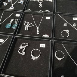 Mehrere Schmucksets in schwarzen Schachteln ausgestellt. Halsketten, Ringe und Ohrringe mit verschiedenen Steinen, einschließlich Türkis und Diamanten. Preise auf Etiketten angegeben.