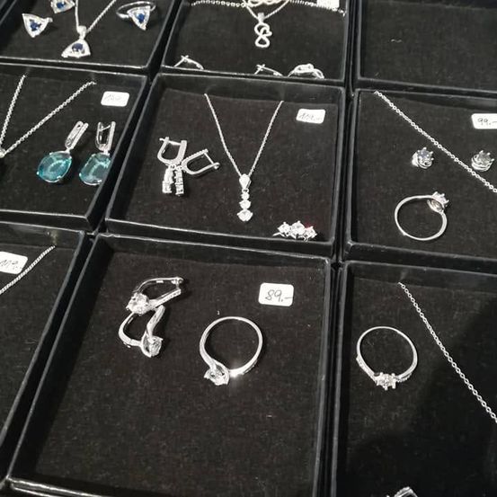 Mehrere Schmucksets in schwarzen Schachteln ausgestellt. Halsketten, Ringe und Ohrringe mit verschiedenen Steinen, einschließlich Türkis und Diamanten. Preise auf Etiketten angegeben.