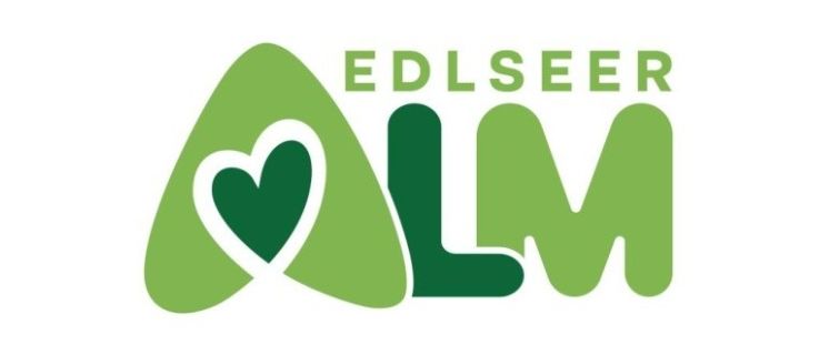 Das Logo von Edlseeer Alm zeigt ein grünes Herzsymbol in einem grünen Dreieck und die Buchstaben 'ALM' in grün.