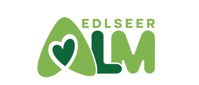 Das Edlsee Alm Logo zeigt ein grünes Herzsymbol und den Text Edlsee Alm in grünen und weißen Farben.