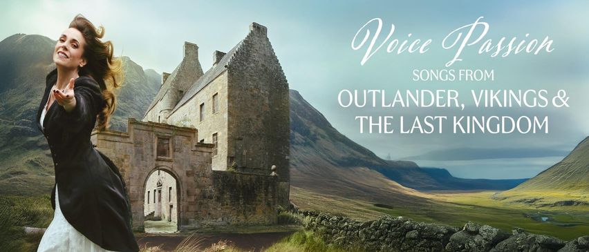 Ein historisches Steingebäude mit mehreren Schornsteinen steht vor einer Kulisse von Bergen und klarem Himmel. Es verfügt über einen steinernen Torbogeneingang.