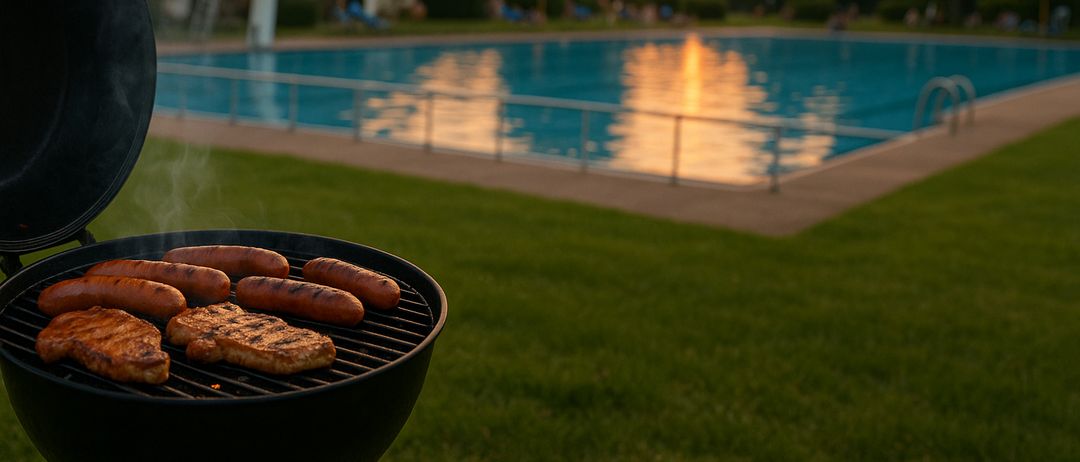 Ein Grill mit Hotdogs und Burgern steht in der Nähe eines Pools, während die Sonne im Hintergrund untergeht.