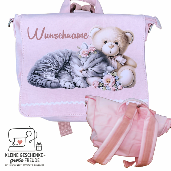 Ein rosa Rucksack mit einem schlafenden Kätzchen und einem Teddybär. Oben steht 'Wunchname'. Eine kleinere rosa Tasche ist auf der Seite zu sehen.