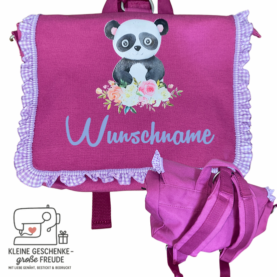 Ein rosa Rucksack mit einem Panda, der Blumen hält und den Text 'Wunschname' darauf hat. Er hat einen lila Rand und ein Band. Ein kleinerer rosa Rucksack ist ebenfalls zu sehen.