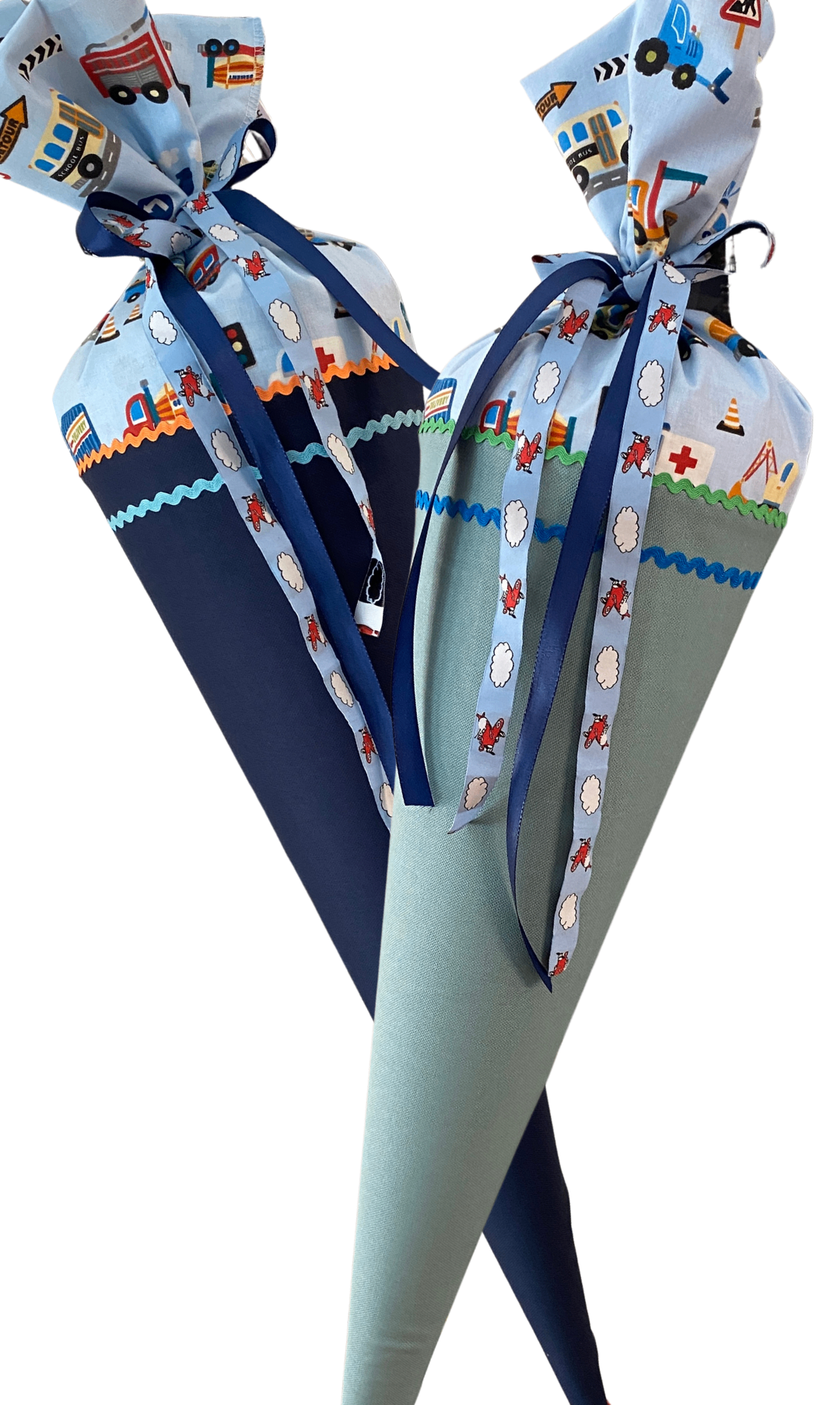 Zwei blaue Stoffröhren mit blauen Bändern. Eine hat ein Bauthema mit Lastwagen und die andere hat ein medizinisches Thema mit einem Kreuz.
