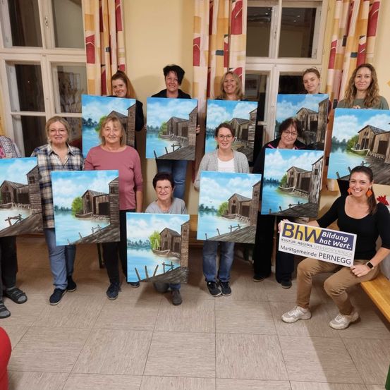 Eine Gruppe von Frauen hält bemalte Leinwände vor einem Fenster. Eine Frau hält ein Schild mit der Aufschrift Bildung hat Wert.