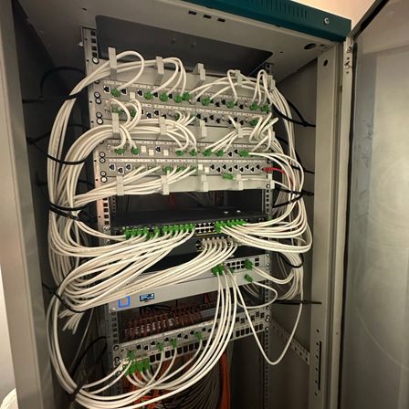 Ein Nahaufnahme eines Netzwerk-Server-Racks mit verschiedenen miteinander verbundenen Geräten, Kabeln und Anschlüssen gefüllt.