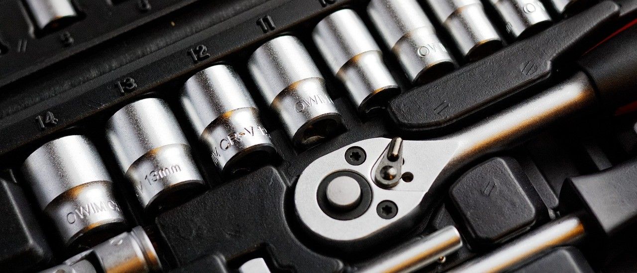 Nahaufnahme einer geöffneten Werkzeugkiste mit verschiedenen Größen von Ringschlüsseln und einem Schraubenschlüssel.