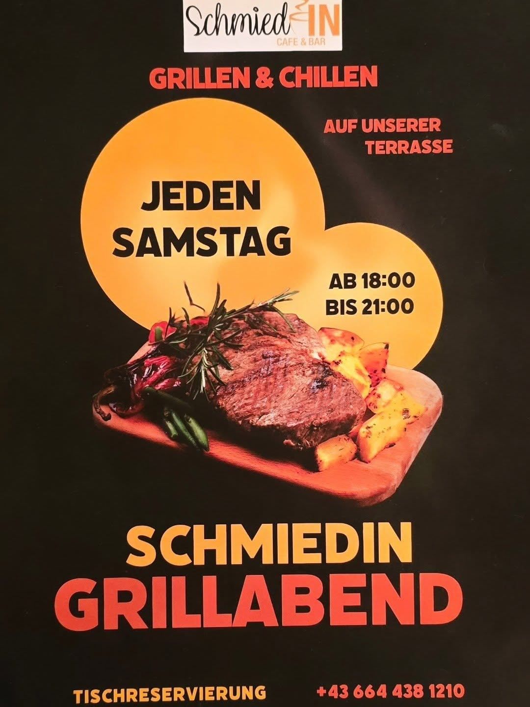 Ein Plakat zeigt ein gegrilltes Steak auf einem Holzteller mit Gemüse. Es steht 'Jedn Samstag' und 'AB 18:00 BIS 21:00' auf einem schwarzen Hintergrund. Der Text 'Schmiedin Grillabend' ist unten.