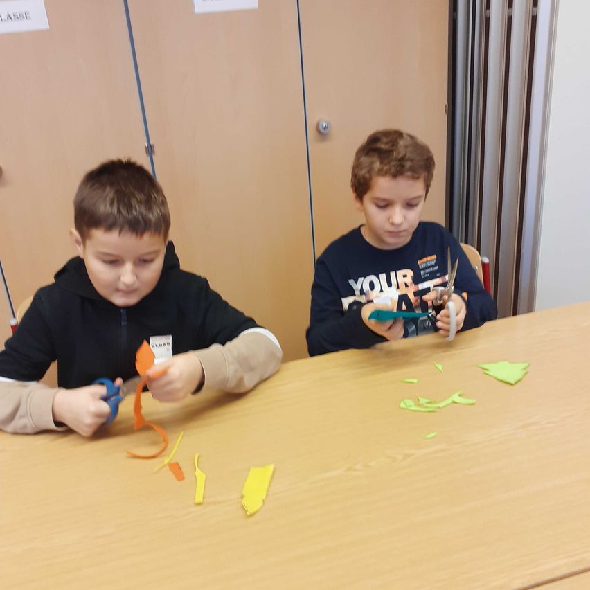 Bild enthält, Person, Student, Boy, Child, Male, Furniture, Table, Wood, Scissors, Text