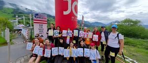 Eine Gruppe von Läufern mit Schildern mit den Worten 'Beginungen' posiert für ein Foto in einem malerischen Außenbereich mit Bergen und Bäumen im Hintergrund.