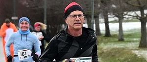 Ein Mann mit der Nummer 119 auf seinem Shirt läuft in einem Marathon mit einer Frau im Hintergrund.