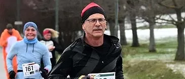 Ein Mann mit der Nummer 119 auf seinem Shirt läuft in einem Marathon mit einer Frau im Hintergrund.