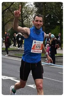 Ein Mann in einem blauen Tanktop läuft in einem Marathon mit der Nummer 579 auf seinem Trikot.