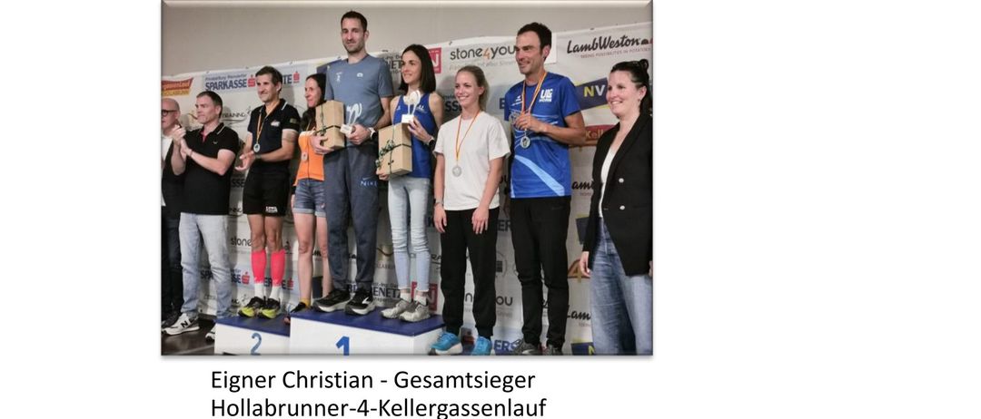 Eine Gruppe von Menschen steht auf einem Podest, einige halten Trophäen, mit einem Banner im Hintergrund.