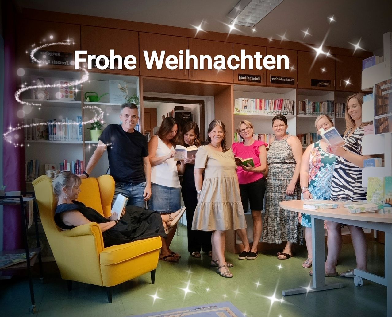 Eine Gruppe von Erwachsenen in einer Bibliothek mit einem Tisch und Bücherregalen. Eine Person sitzt in einem Stuhl und liest. Die Überschrift lautet 'Frohe Weihnachten.'