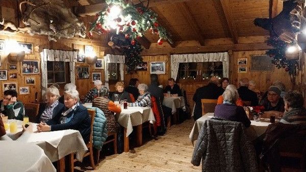 Ein Restaurant voller Menschen, die an Tischen sitzen, trinken und plaudern, mit Weihnachtsdekorationen, die von der Decke hängen.
