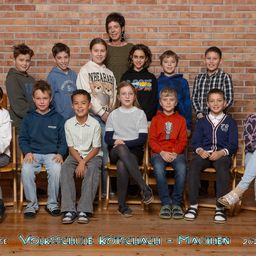 Eine Gruppe von Kindern und einer Frau posiert für ein Foto vor einer Ziegelwand, mit dem Text 'Volksschule Kotschach - Mauthen 2023' unten.