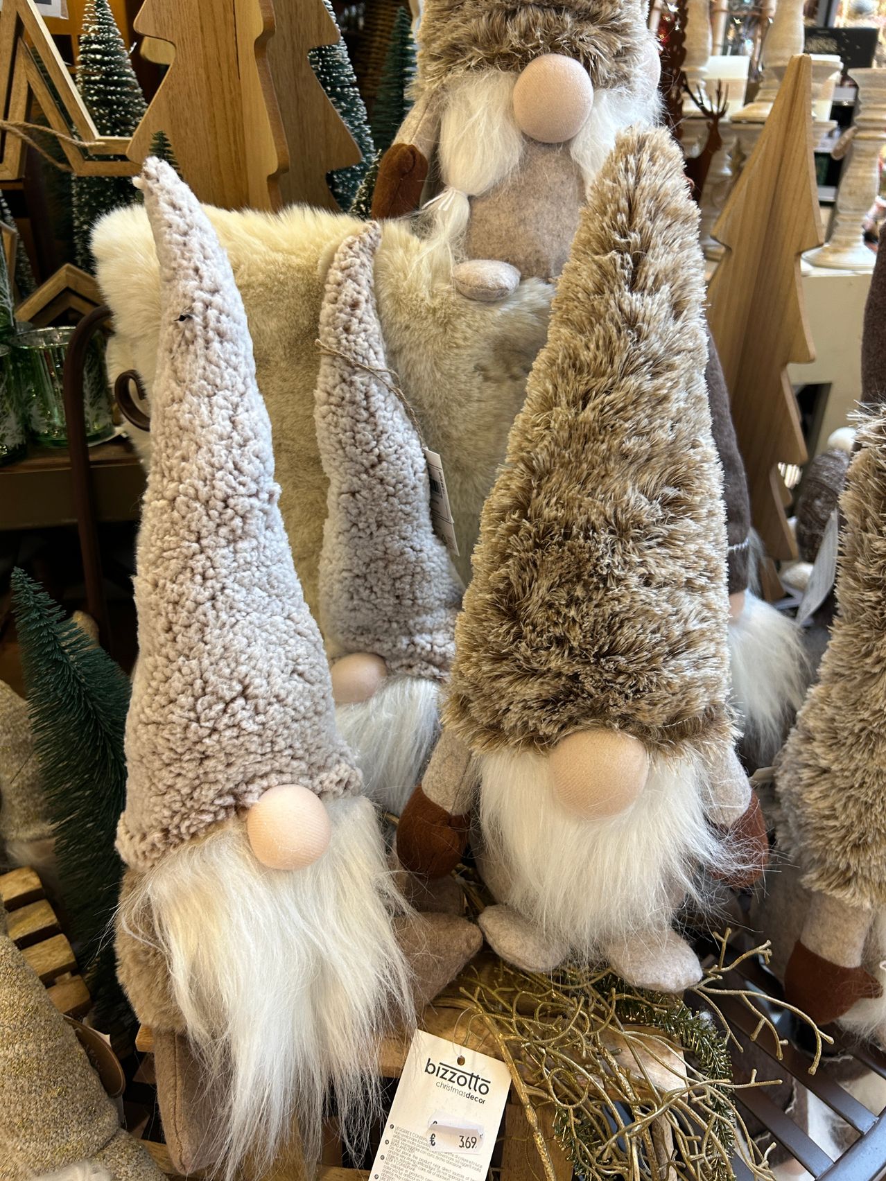 Eine Ausstellung von Zwergen mit flauschigen Mützen, die eng beieinander in einem Geschäft stehen, mit verschiedenen Winterdekorationen im Hintergrund.