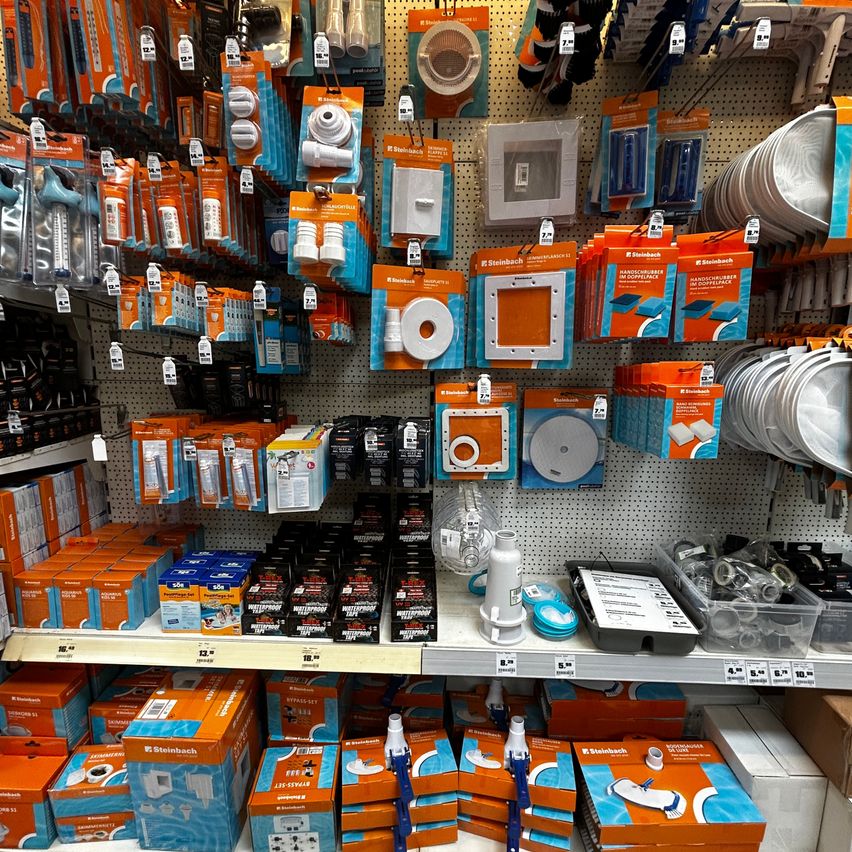 A store with a variety of orange and blue product packaging displayed on shelves and pegboards. The products include items like waterproof seals, brushes, and other household items.