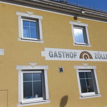 Die Vorderseite eines gelben Gebäudes namens Gasthof Zum Braunen Hirschen mit mehreren Fenstern und einem Logo.
