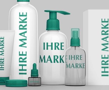 Eine Auswahl an Hautpflegeprodukten, einschließlich Flaschen und Tuben, mit der Aufschrift 'IHRE MARKE', auf einem grauen Hintergrund präsentiert.