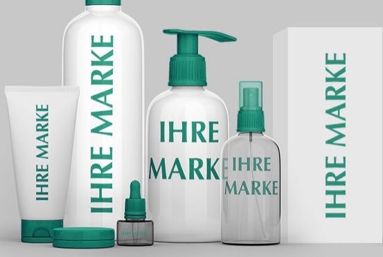 Eine Auswahl an Hautpflegeprodukten, einschließlich Flaschen und Tuben, mit der Aufschrift 'IHRE MARKE', auf einem grauen Hintergrund präsentiert.