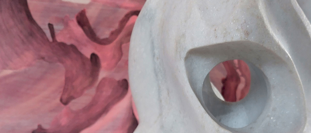 Eine weiße Skulptur mit einer kreisförmigen Öffnung ist vor einem rosa Hintergrund ausgestellt, möglicherweise ein Kunstwerk.