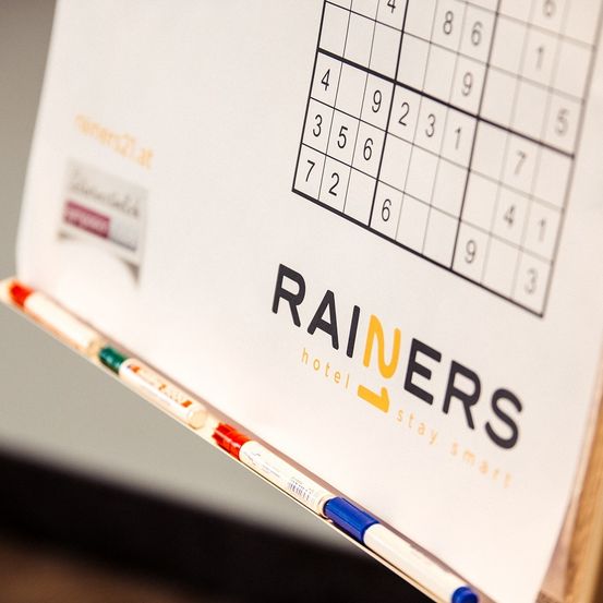 Ein Sudoku-Rätsel auf einer weißen Tafel mit Markern, betitelt 'RAINERS hotel stay smart'.