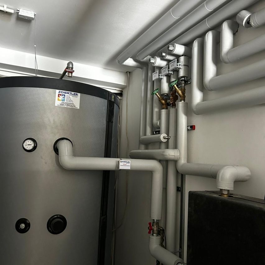 Ein Raum mit einem Metalltank und Rohren, verbunden mit einem schwarzen Kasten auf der rechten Seite.