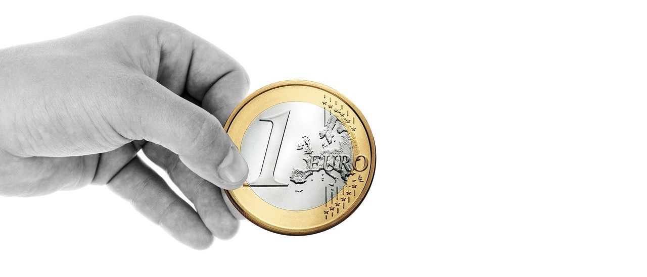 Eine Hand hält eine gold- und silberfarbene Münze mit '1 EURO' darauf. Die Münze ist glänzend und gut verarbeitet.