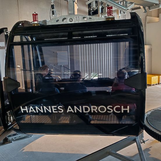 Das Innere einer Hannes Androsch Gondelbahn mit einer Glastür, die Menschen im Inneren zeigt.