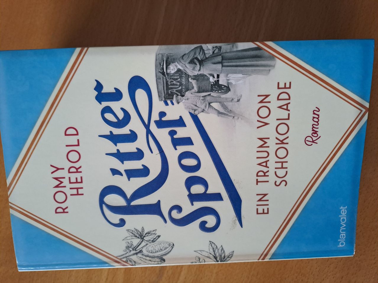 Der Buchdeckel zeigt eine historische Szene mit zwei Personen, eine in Uniform und die andere in einem Kleid, auf einer Holzoberfläche.