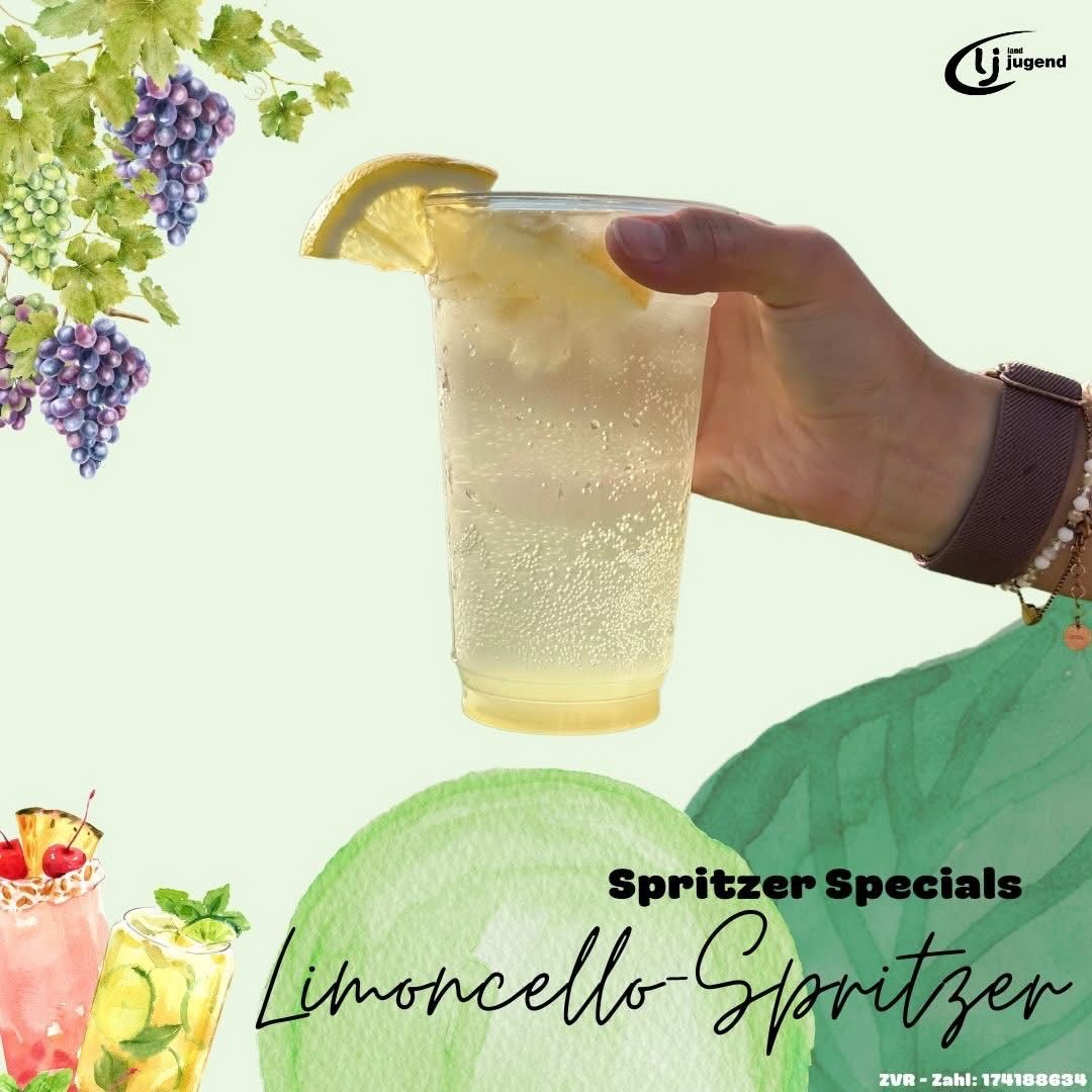 A hand holding a glass of Limoncello Spritzer. The glass contains a clear liquid with a lemon slice and a cherry on top. The background shows a grape vine and other drinks.