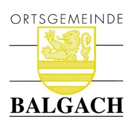 Das Bild zeigt ein Logo für Balgach mit einem gelben Schild, einem Löwendesign und der Aufschrift 'Ortsgemeinde Balgach' darüber.