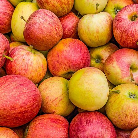 Ein Nahaufnahme von einem großen Haufen roter und gelber Äpfel. Die Äpfel sind ordentlich angeordnet und zeigen ihre glänzenden und lebendigen Farben.