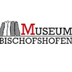 Das Logo des Museums Bischofshofen zeigt eine stilisierte Darstellung einer Bergkette mit einem roten 'M' und den Worten 'Museum Bischofshofen' darunter.